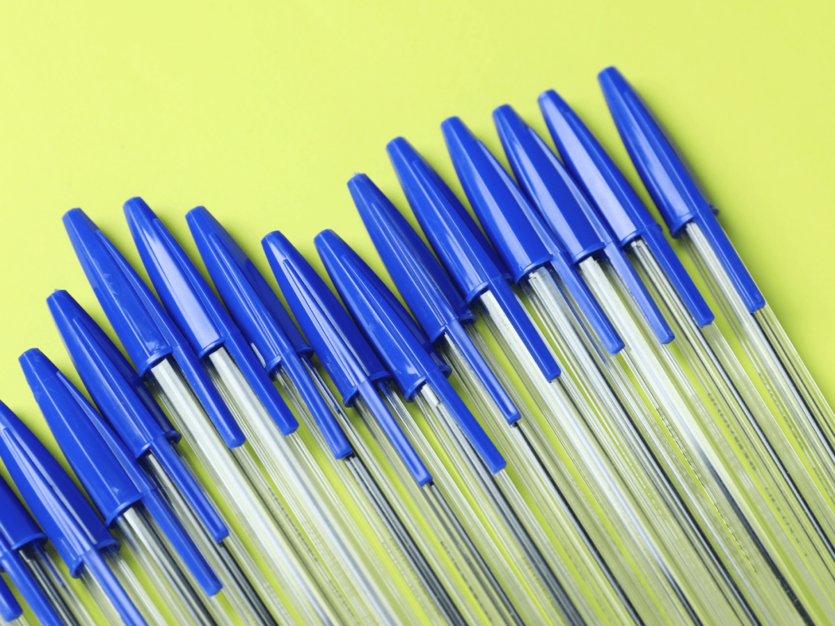 Mehrere blaue Kugelschreiber auf gelben Untergrund.