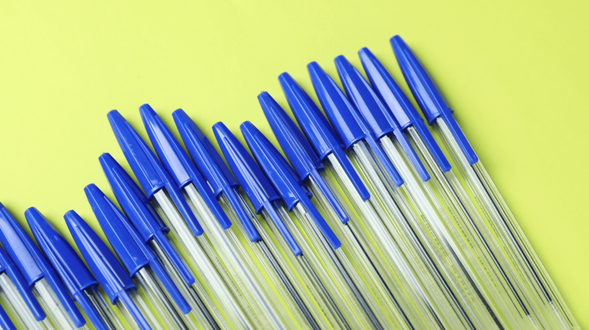 Mehrere blaue Kugelschreiber auf gelben Untergrund.