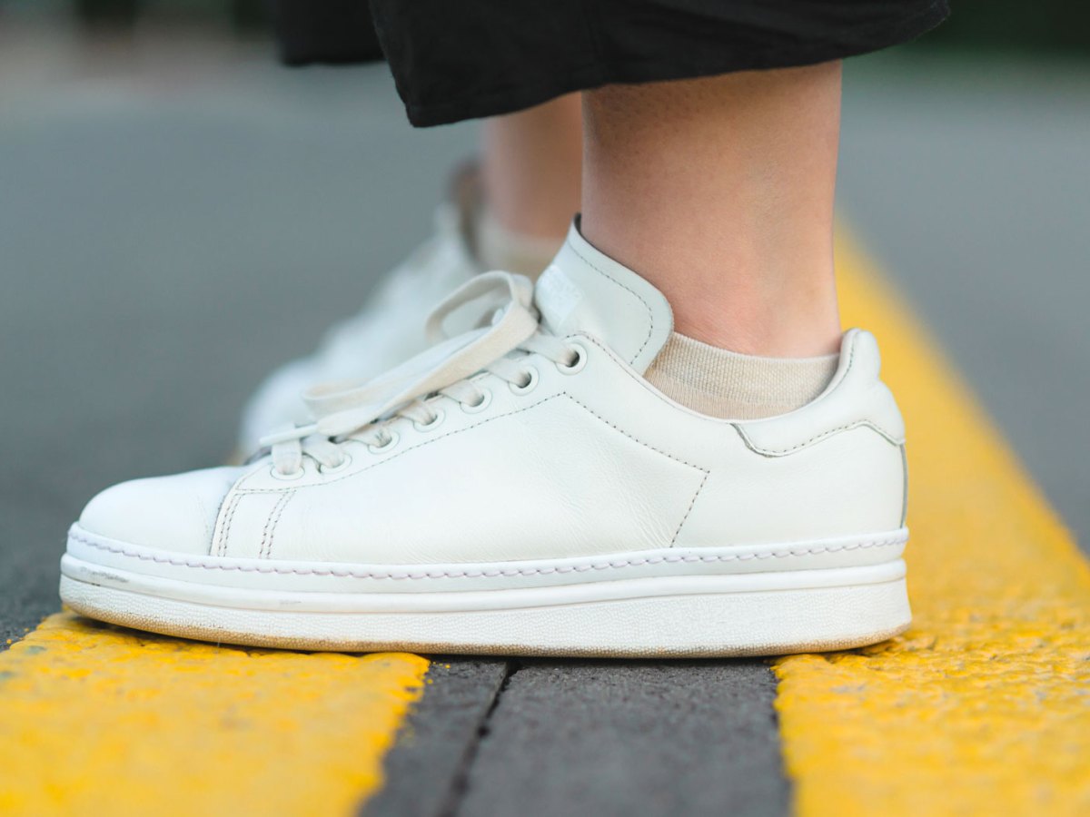 Frauenbeine mit weißen Sneaker als Bild für Schweißfüße in Sneakers