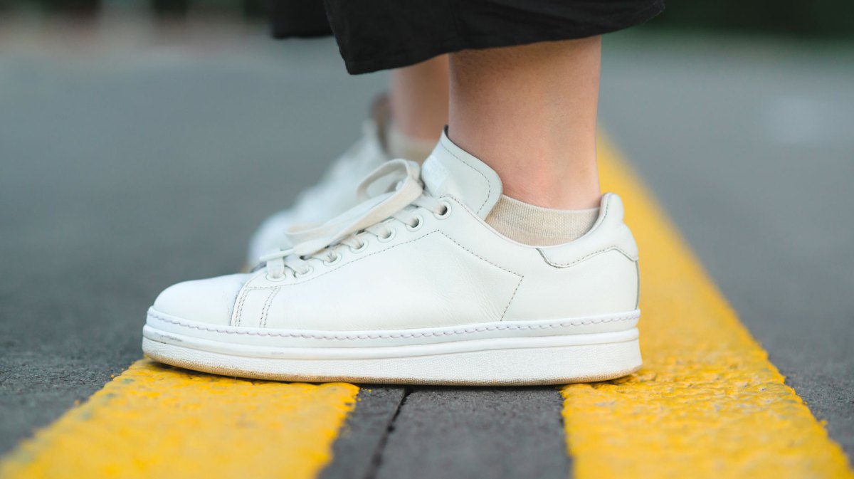 Frauenbeine mit weißen Sneaker als Bild für Schweißfüße in Sneakers