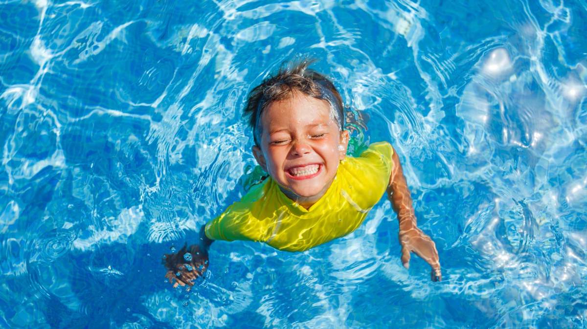 Junge im Pool mit gelbem Schwimmshirt.