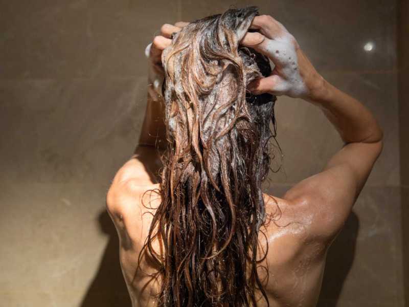 Frau wäscht sich unter der Dusche die Haare