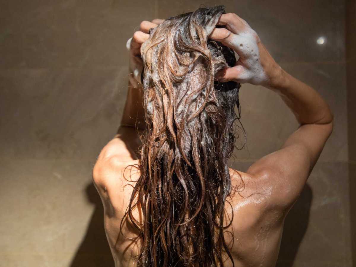 Frau wäscht sich unter der Dusche die Haare