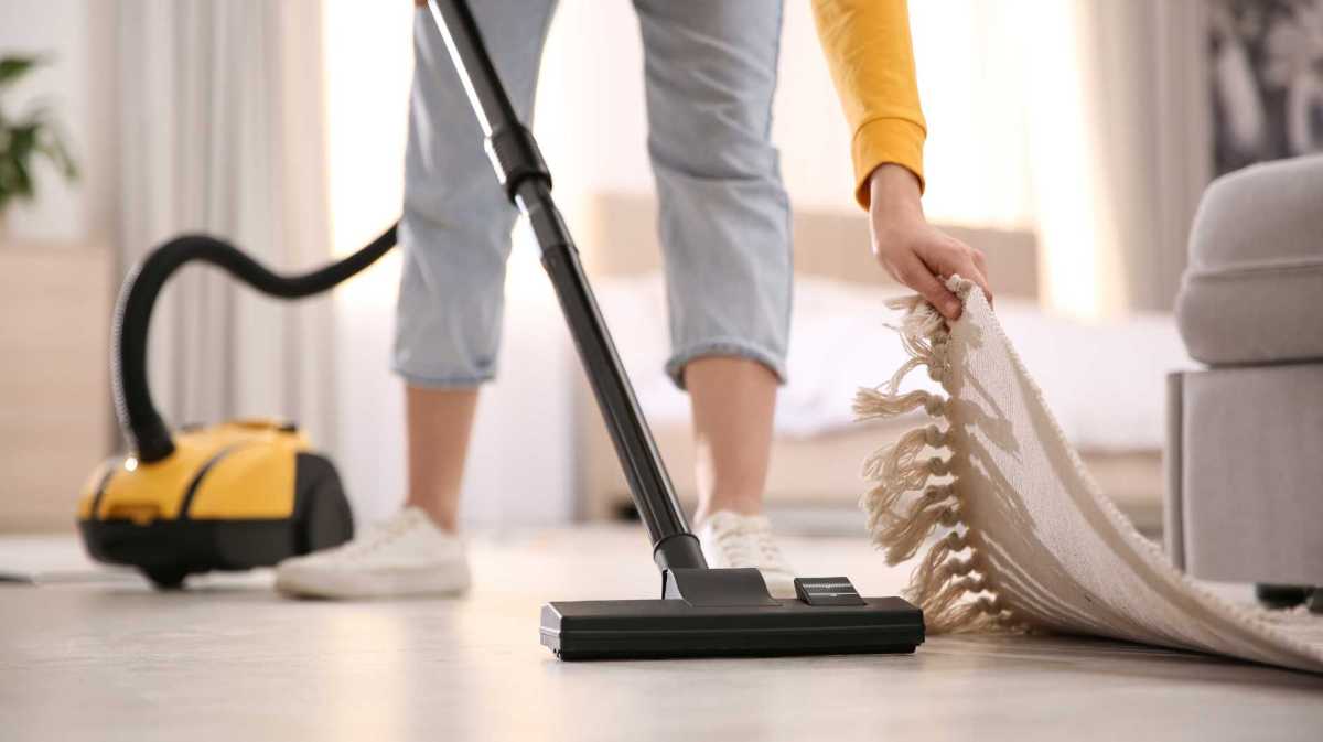 Frau saugt unter einem Teppich