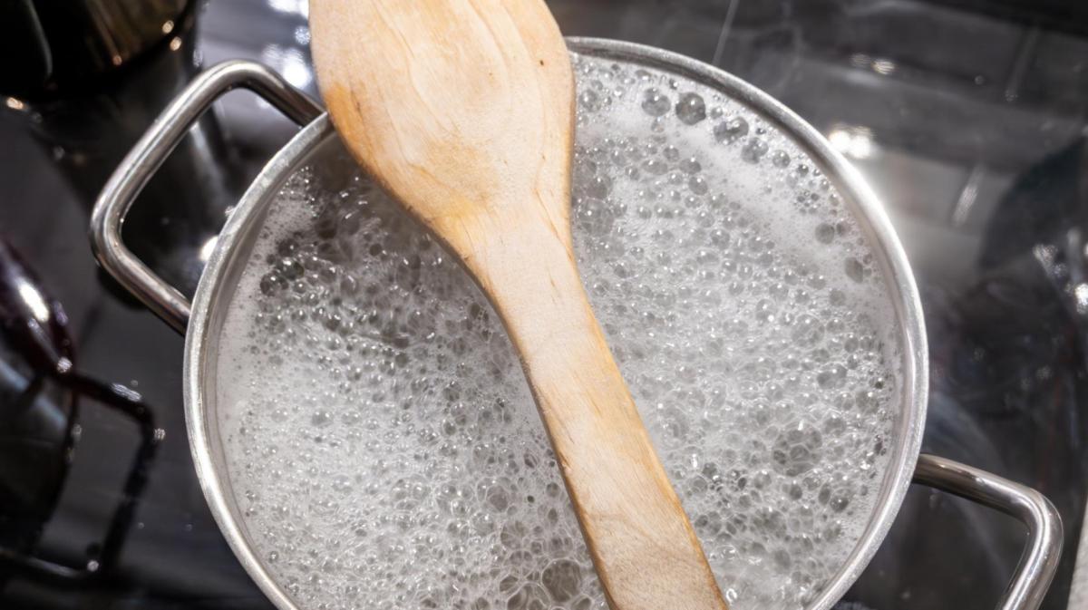 Holzlöffel liegt auf einem Topf mit kochendem Wasser.