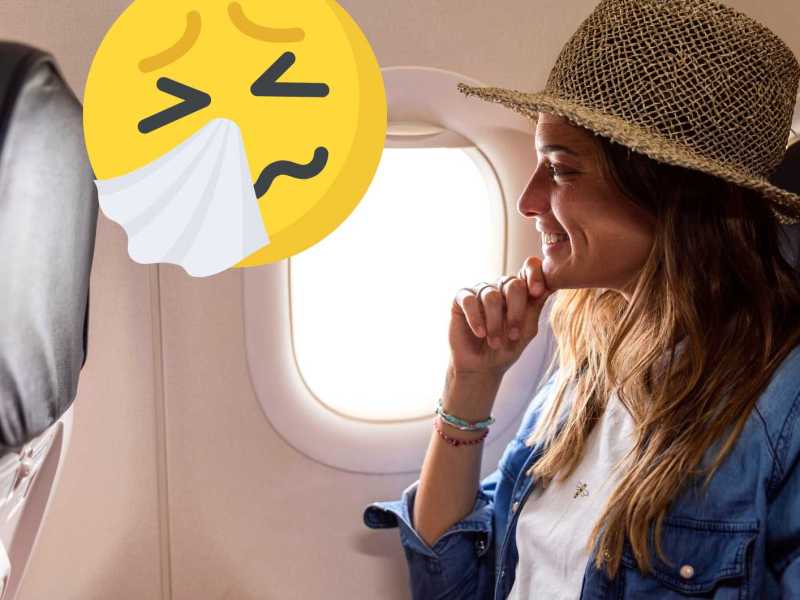 Frau sitzt im Flugzeug am Fenster und trägt sommerlichen Hut