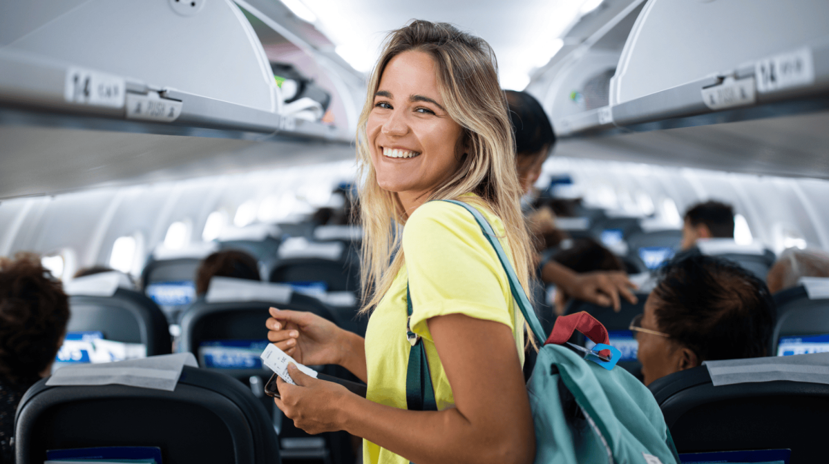 Junge Frau steht im Gang im Flugzeug.