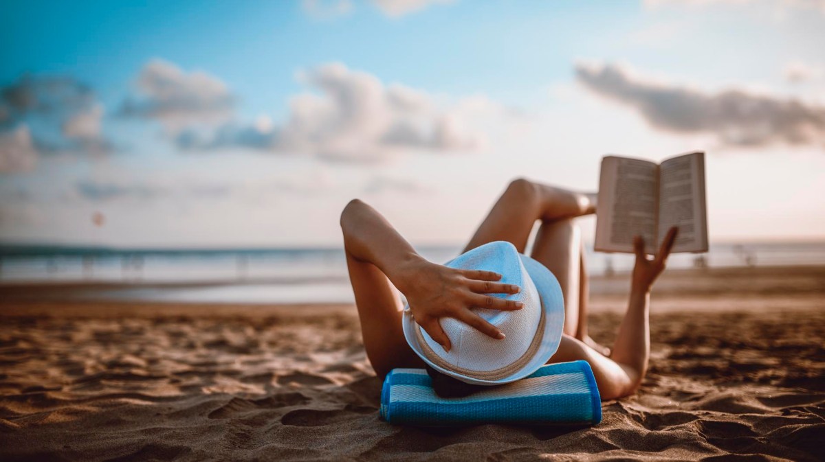 Frau liest entspannt am Strand