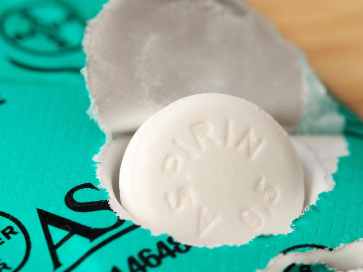 Aspirin-Tabletten werden aus einer grünen Packung gedrückt.