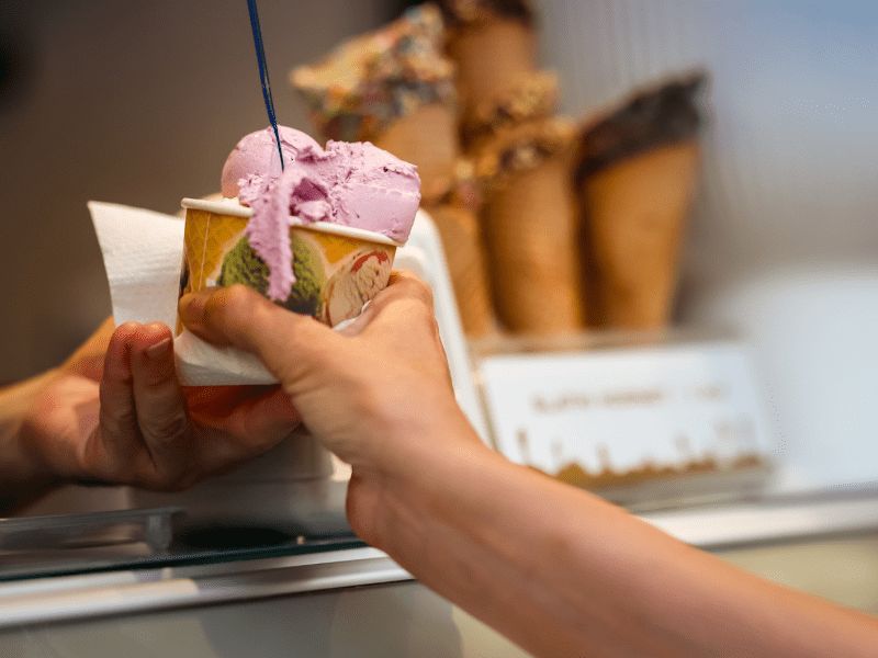 In der Eisdiele wird ein Eisbecher über die Theke gereicht