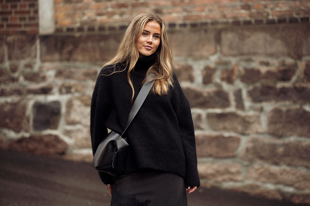 Eline Hynne Knoff wears black pants, black silk dress with lace, black sweater and a black Acne Studio bag outside the Wilhelmina show event during Oslo Fashion Week on August 27, 2025 in Oslo, Norway
