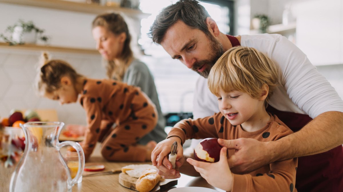 Familie bereitet gemeinsam das Frühstück zu.