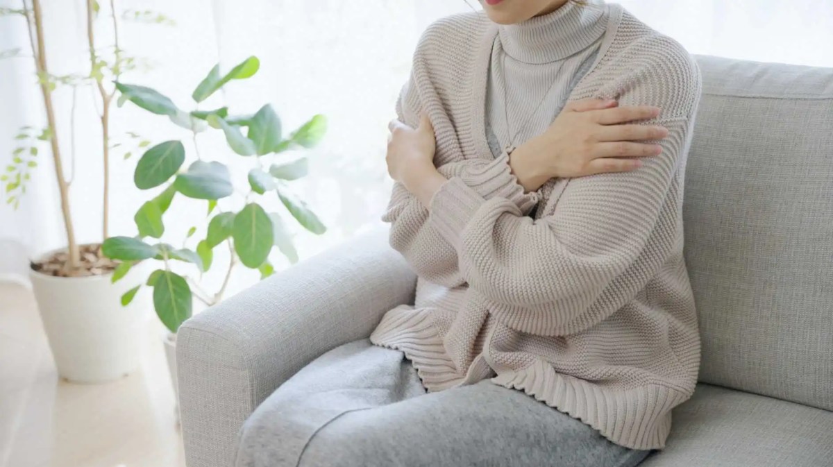 Frau sitzt auf dem Sofa und friert