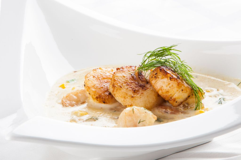 Suppe mit Jakobsmuscheln in einer weißen Schüssel.